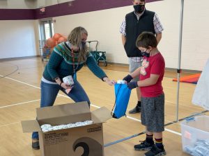 Explore! Community School student stuffing backback with supplies for people experiencing homelessness. 